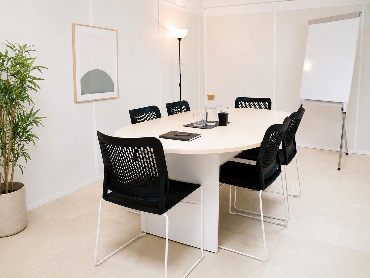 Sala de reuniones luminosa con mesa ovalada, sillas negras y pizarra